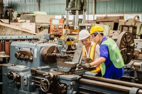 Workers operating industrial machinery in a manufacturing plant.