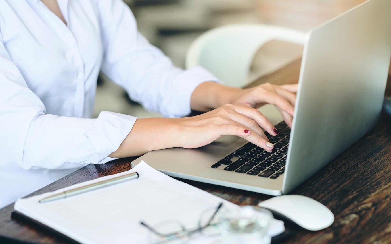 Cropped shot of businesswoman using laptop computer while sitting at office desk
