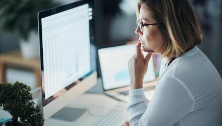 Businesswoman analyzing SharePoint data on computer screen.