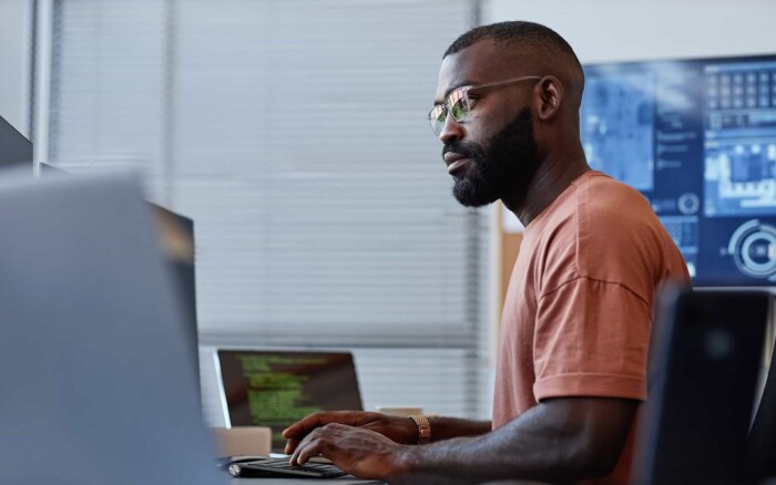 Side view portrait of software developer using computer in high technology office