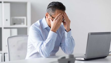 Excel Troubleshooting Frustration | i3solutions Frustrated man fixing Excel issues on his laptop at work.