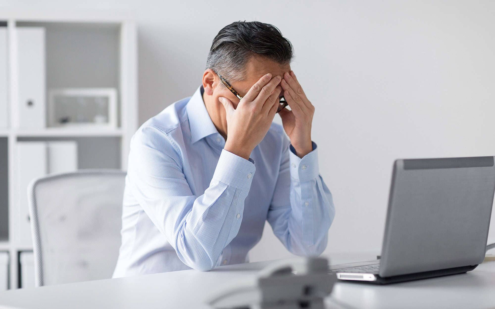 Excel Troubleshooting Frustration | i3solutions Frustrated man fixing Excel issues on his laptop at work.