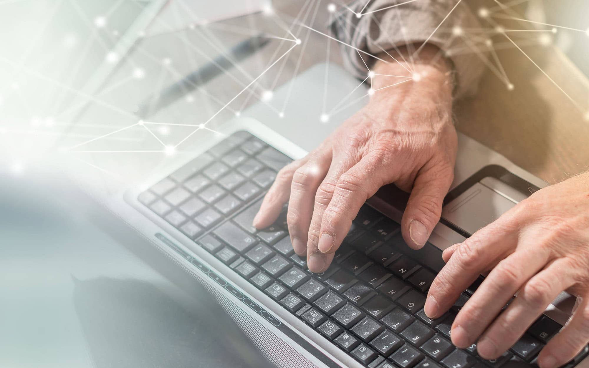 Hands typing on a laptop keyboard with digital network overlay.