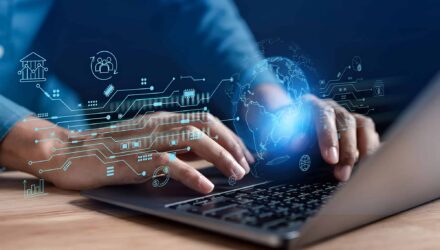 Hands typing on a laptop with digital tech icons and globe overlay, representing IT solutions.