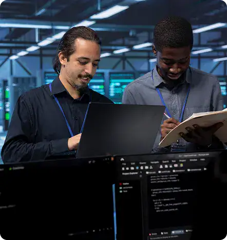 IT Professionals Collaborating in Data Center | i3solutions IT professionals reviewing a legacy systems modernization plan on a laptop.