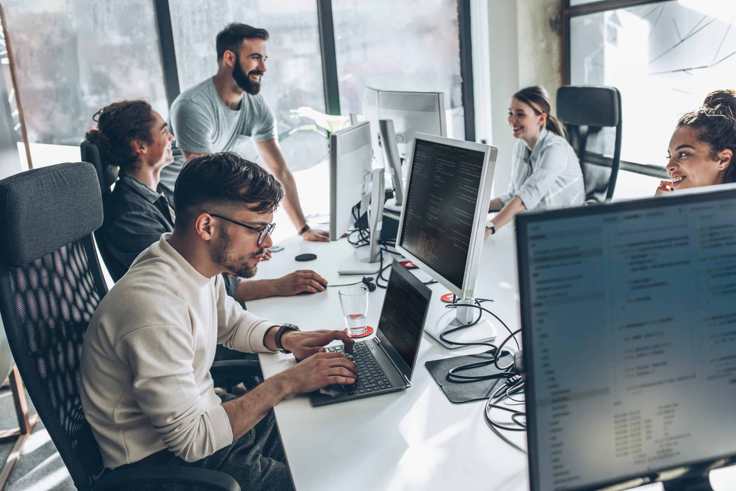 Team collaboration in a modern office environment with diverse professionals working on computers. | i3solutions Remote and on-site teams collaborating on Microsoft-centric enterprise projects.