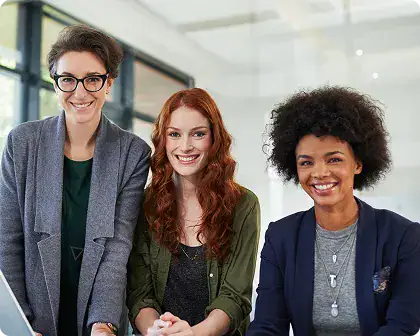 Diverse Business Team Collaboration | i3solutions Three smiling women coworkers pose together in a bright, modern office, suggesting a collaborative team moment.