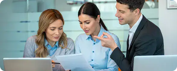Professional Business Meeting for Azure Developers | i3solutions Three coworkers review a document together in a bright office, with laptops on the desk and one person pointing at the pages.