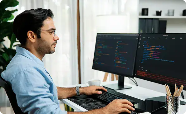 Hire Power Platform Developers | i3solutions Power Platform architect reviewing application code across dual monitors in an enterprise delivery environment