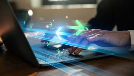 Innovative Data Transfer Technology | i3solutions Person using a laptop with digital data transfer graphics overlay.