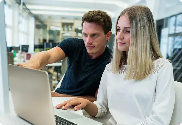 Collaborative Microsoft Expert Consultation | i3solutions Two professionals collaborating on a laptop in a modern office setting.