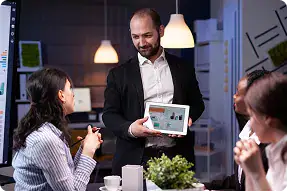 Business Meeting with Digital Presentation | i3solutions Business professional presenting digital tablet to team in modern office.