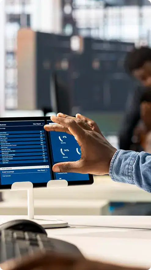 Business professional using tablet in office | i3solutions Person using tablet with data charts in modern office environment.