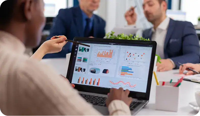 Business Meeting Analyzing Data Reports | i3solutions Business professionals reviewing data analytics on a laptop during a meeting.
