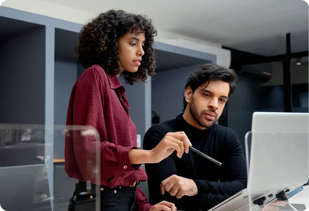 Two professionals analyzing data on a computer in an office setting.