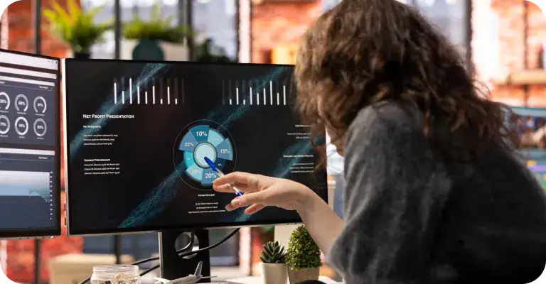 Person analyzing data on dual monitors for IT systems analysis.