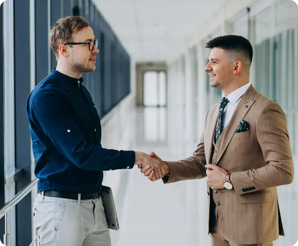 External Platform Integration System Connectivity Two businessmen shaking hands in a bright, modern office corridor.