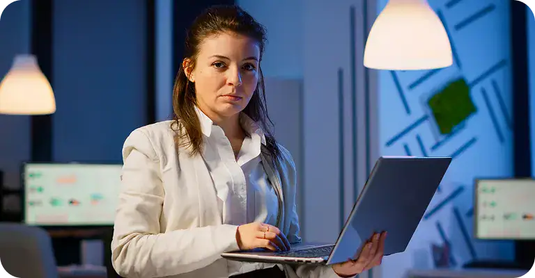 Businesswoman Using Laptop in Office | i3solutions Businesswoman working on laptop in modern office with digital screens.