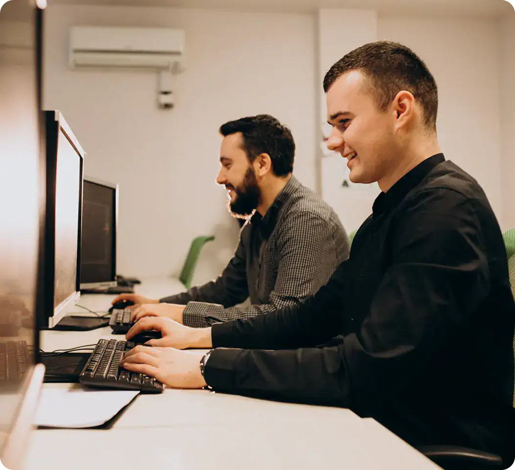 IT Professionals Working on Computers | i3solutions Two IT professionals working on desktop computers in an office setting.
