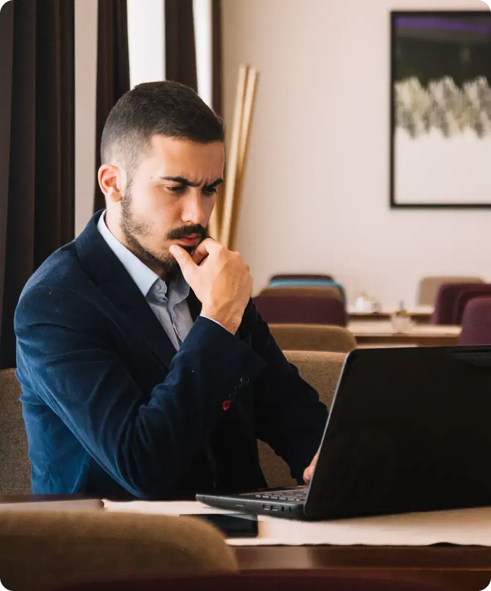 Focused businessman working on laptop in modern office setting.