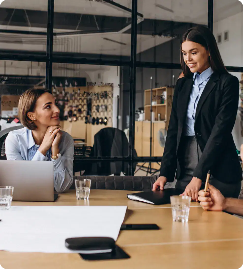 Two women in business attire having a discussion in a modern office.