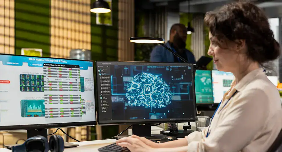 Data analyst working with multiple monitors displaying data and brain graphics.