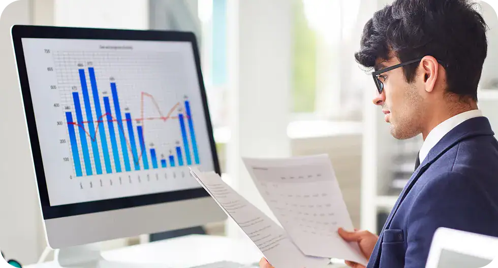 Business professional reviewing data and analytics on a computer screen.