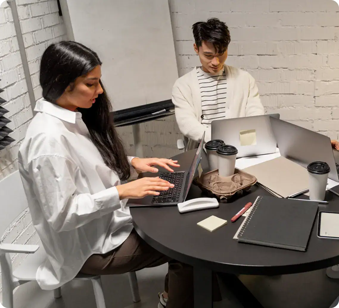 Team Collaborating on Data Analysis | i3solutions Two professionals working on laptops in a modern office setting.