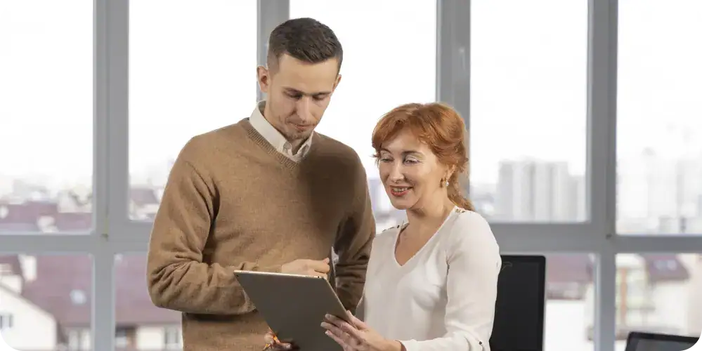 Business Intelligence & Reporting Team Meeting | i3solutions Business professionals discussing data on a tablet in an office setting.