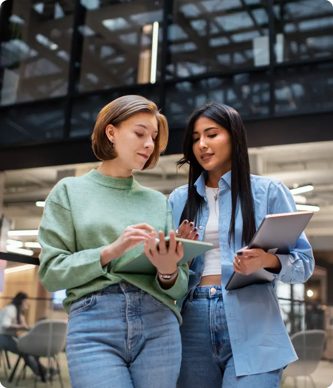 Women Using Tablets in Modern Office | i3solutions Two women using tablets in a modern office environment.
