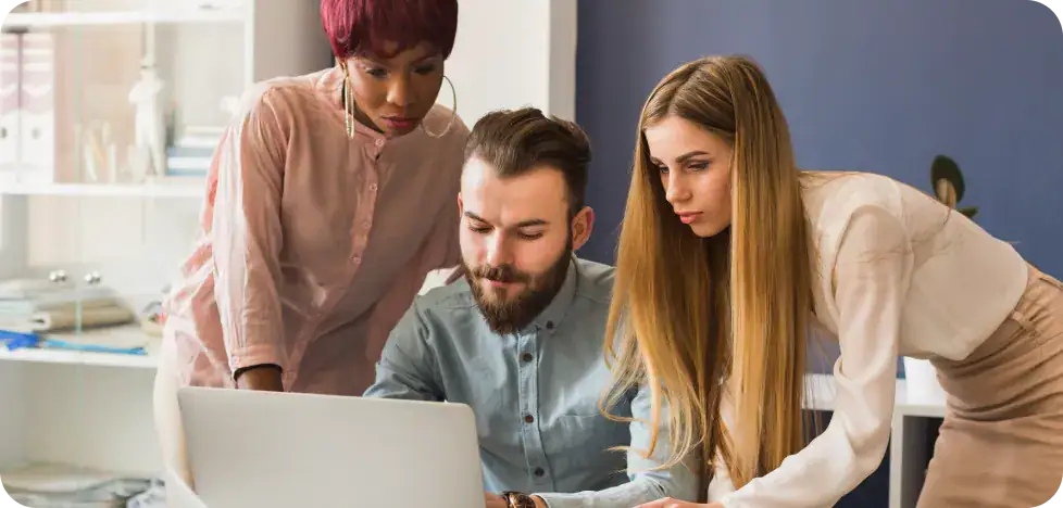 Team working together on a laptop for workflow automation solutions.