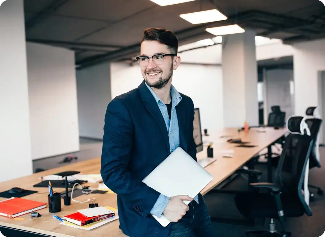 Professional Businessman in Modern Office | i3solutions Business professional holding a laptop in a contemporary office setting.
