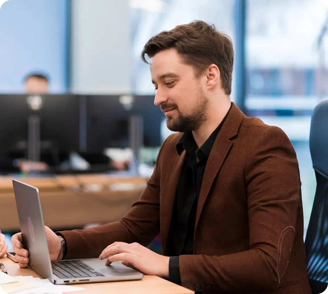 Business professional using laptop at desk in modern office environment.