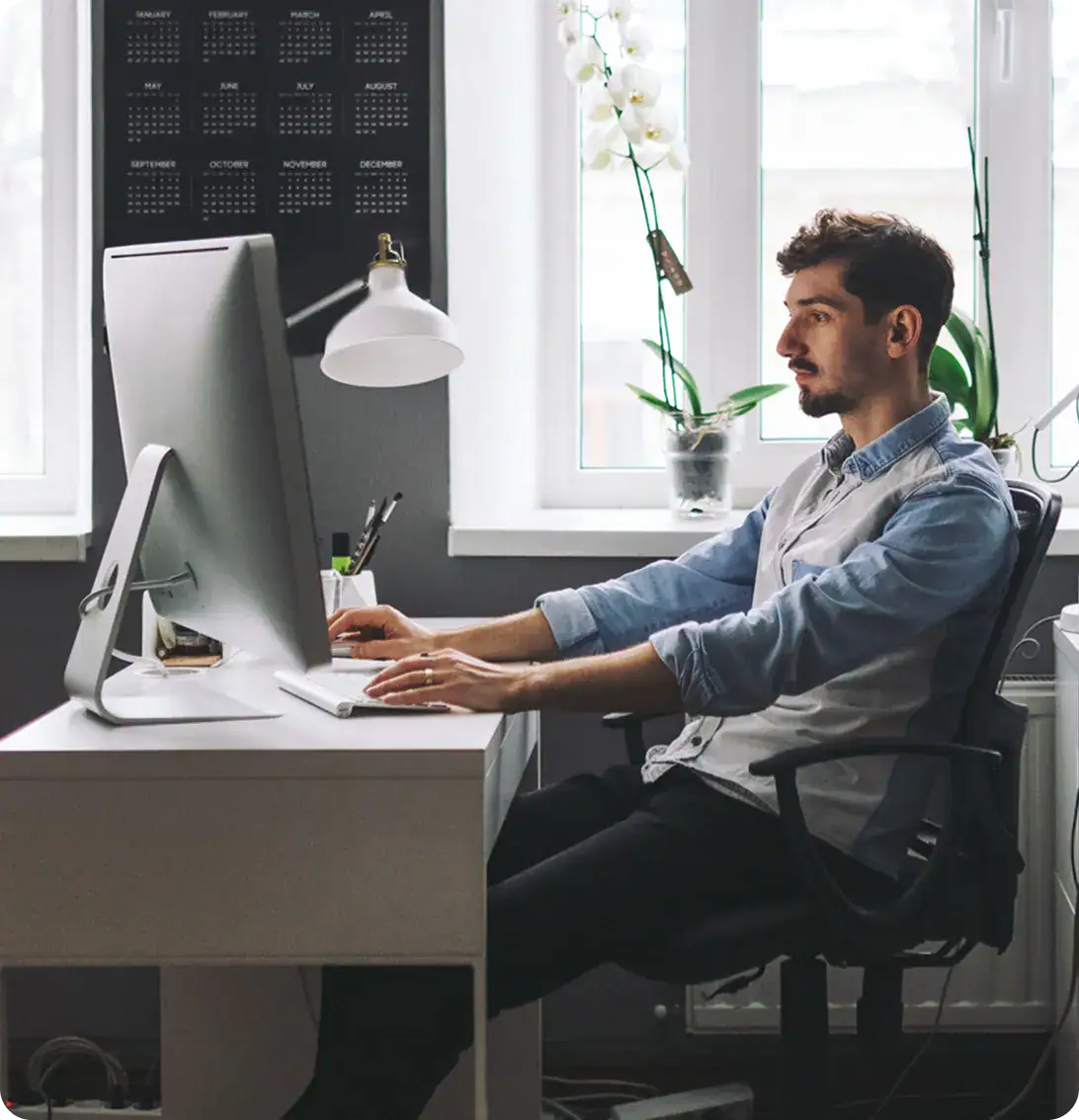 Young male software developer working on desktop computer in modern office.