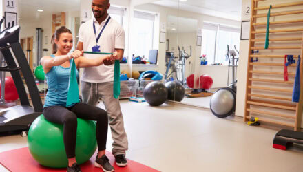 Physical therapy session with a therapist and a woman using an exercise ball.
