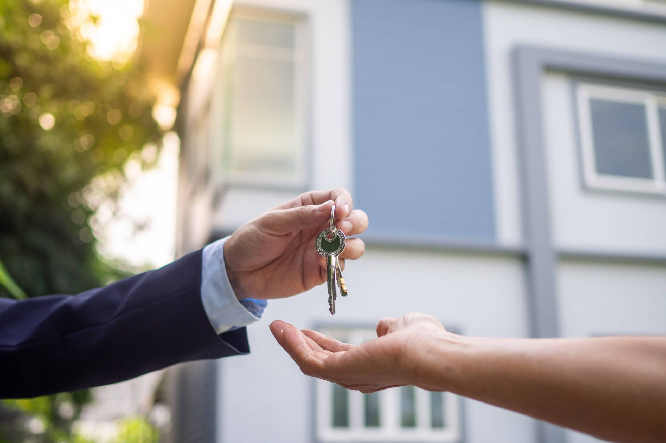 Person Handing Over Keys in Front | i3solutions Person handing over keys in front of a house during daytime.