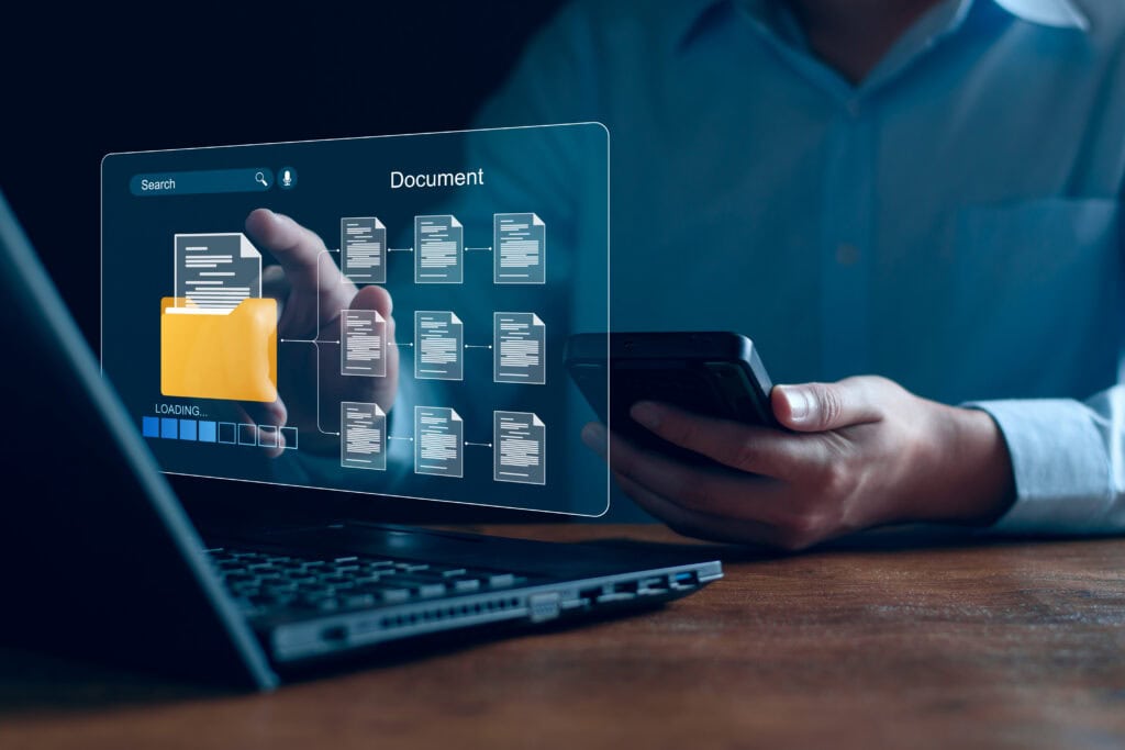 Business person using smartphone with digital document interface and laptop.