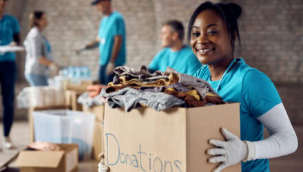 Smiling woman holding a donations box at a charity event.