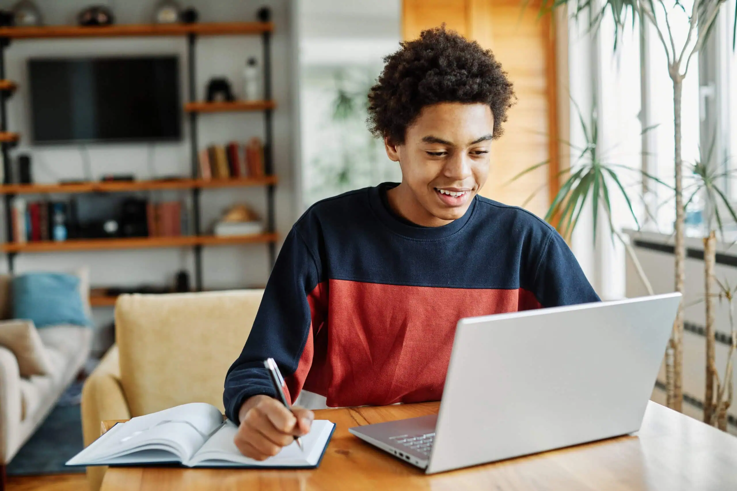 Young Woman Working on a Laptop | i3solutions Young woman working on a laptop with a notebook and pen at home.
