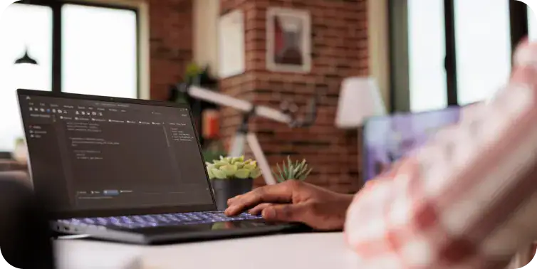 Software Developer Working on Laptop Person coding on a laptop with a dark-themed code editor open.