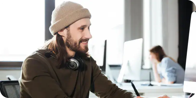 Creative professional working at desk Young man with headphones working at computer in modern office.