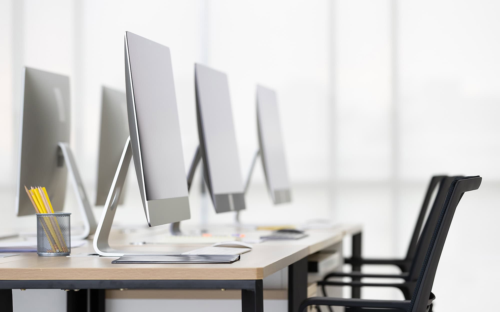 Modern office workspace with multiple desktop computers and chairs.
